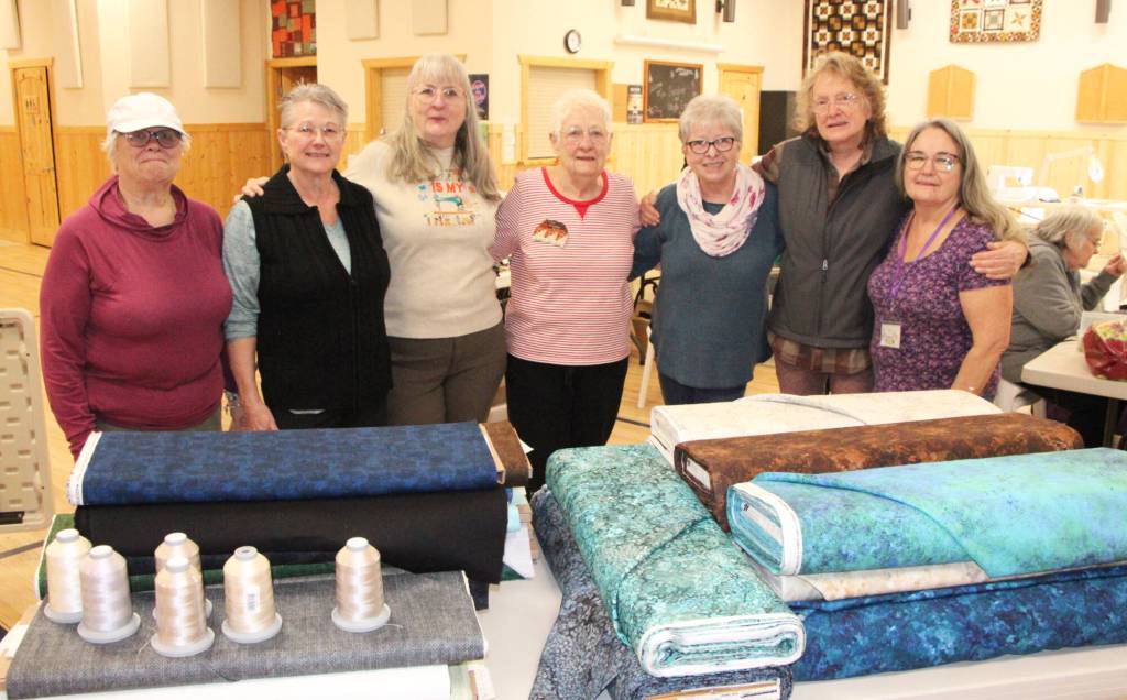 Members of the Log Cabin Quilters pose for a photo in front of $6,000 worth of quilting supplies donated to them by the Four Rivers Co-operative. (Patrick Davies photo - 100 Mile Free Press)